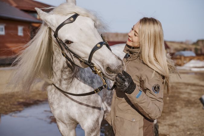Warm dressed woman with gray horse outside