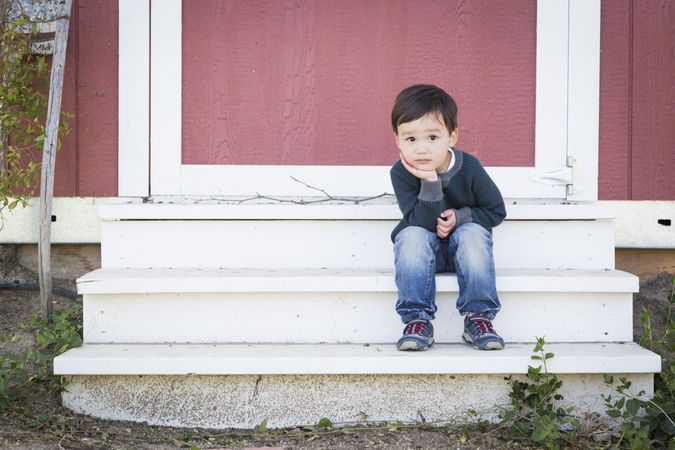 Cute Young Boy Sitting on the Steps of a Barn