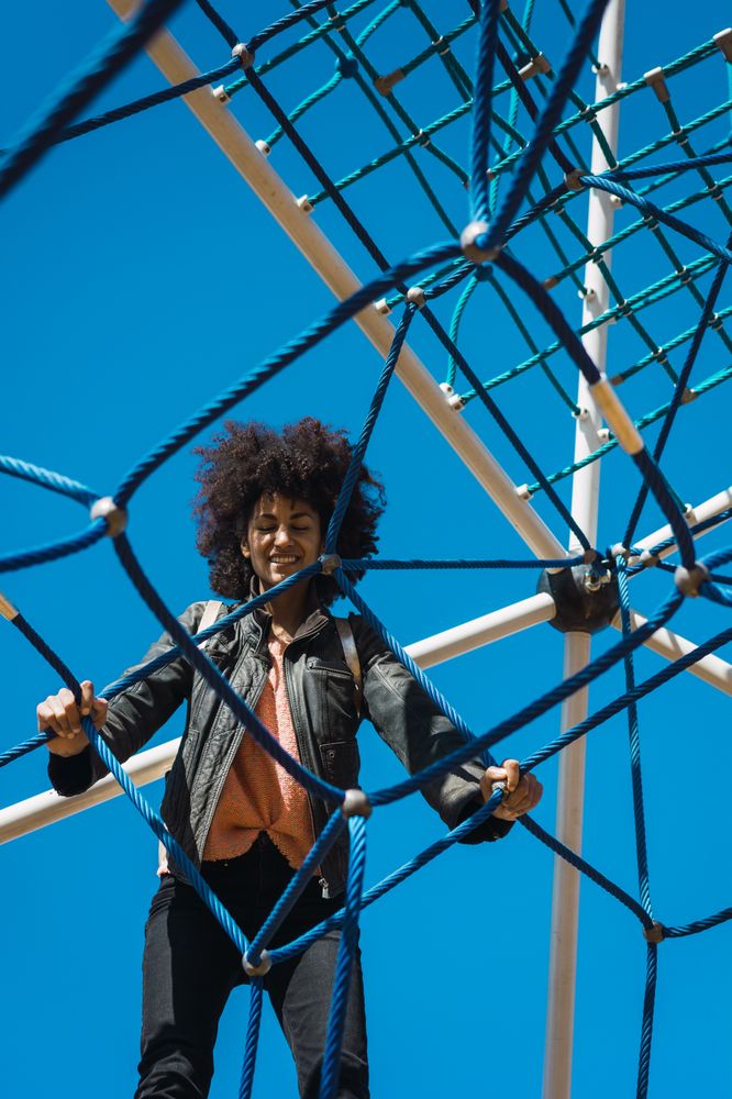 Woman with afro hair climbing by children's attractions.