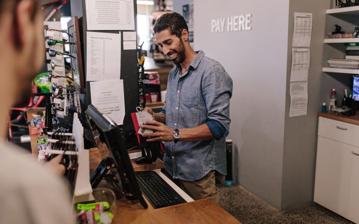 Man taking payment at the counter of a store