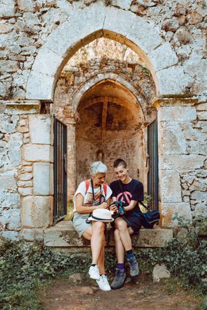 Stylish young woman showing photography to older female friend on stony steps