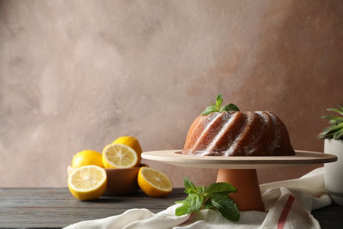 Cake with powder sugar and mint on wooden background, space for text