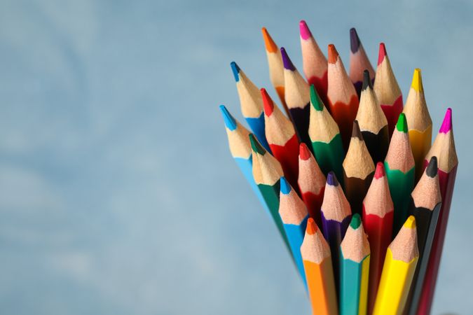 Multicolored pencils against light blue background, closeup