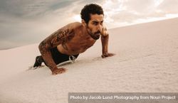 Fit man doing push-ups over sand dunes 5nlMZb