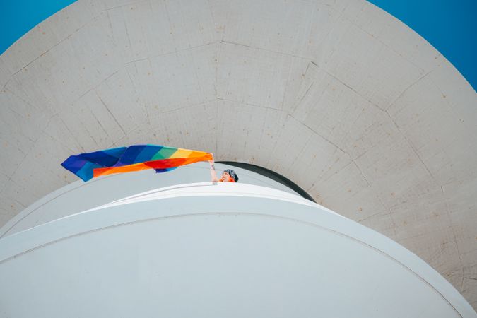 Person in a building waving rainbow flag