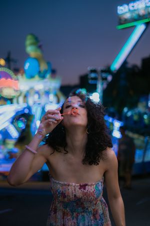 Woman in amusement park blowing bubbles