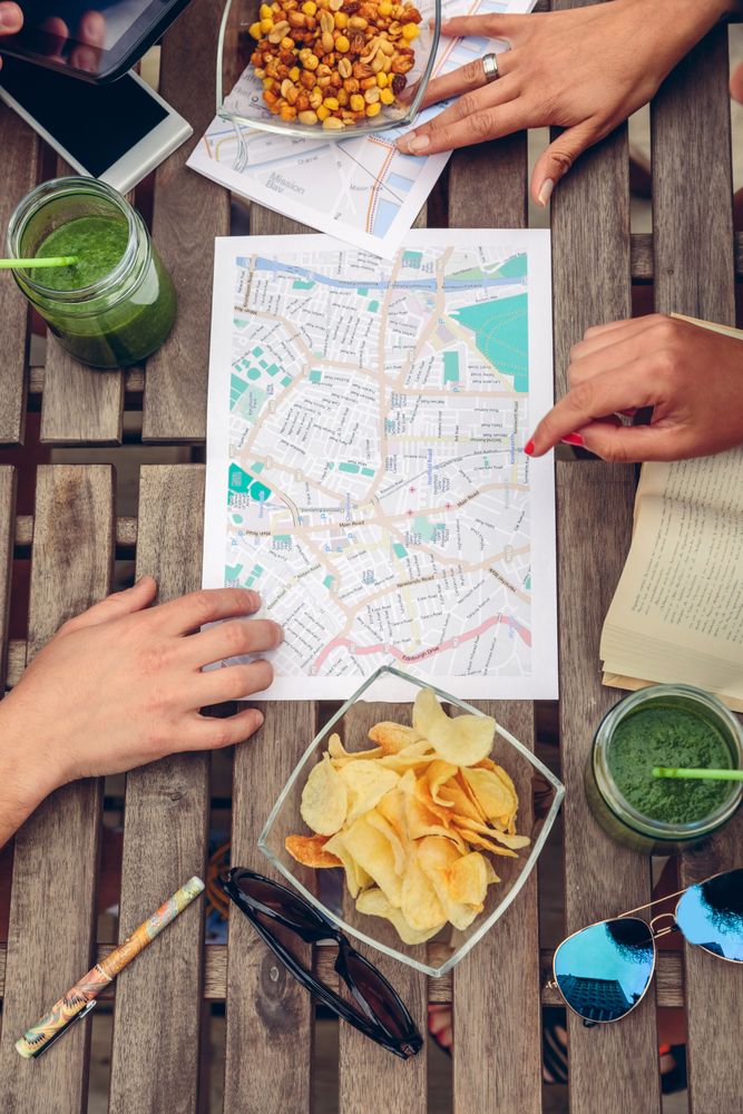 Hands of friends sitting on bench reviewing maps