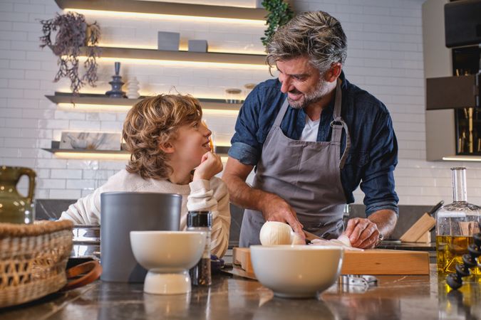 Content father cutting onion near kid
