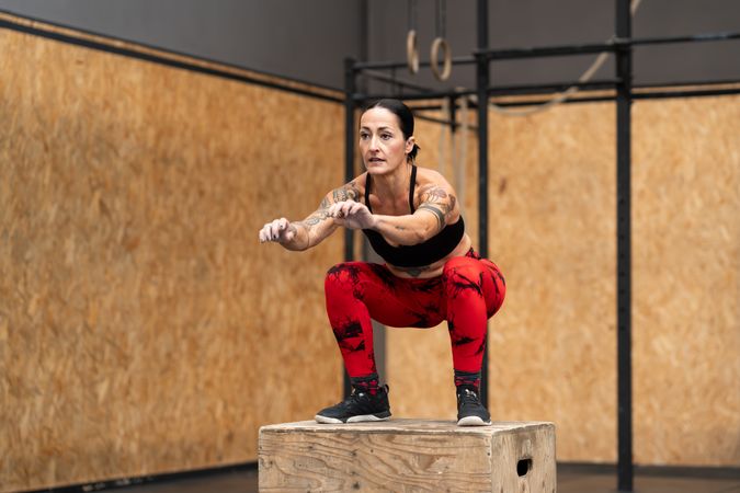 Fit woman doing box jump in gym