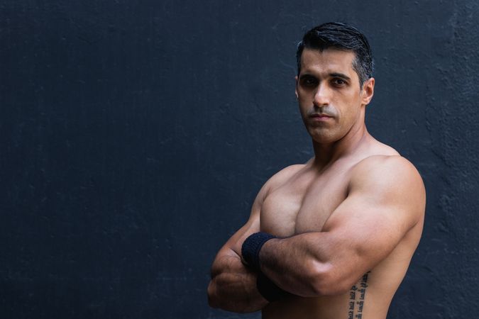 Positive shirtless Hispanic sportsman near wall