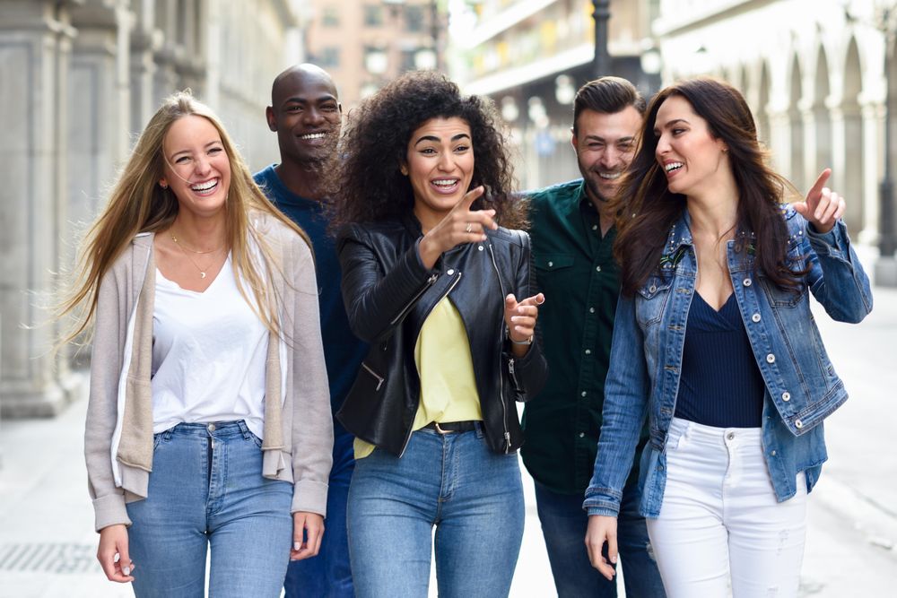 Friends walking down down city street and smiling together