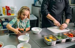 Chef preparing ingredients for healthy poke bowl with his daughter in restaurant kitchen