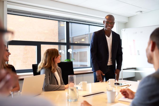 Smiling businessman standing and leading a meeting in a room with a dry erase board