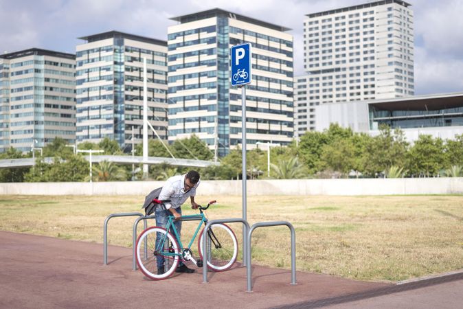 Male with colorful bicycle parking at rack in urban landscape