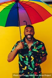 Black male smiling under colorful umbrella 5Qp9e0