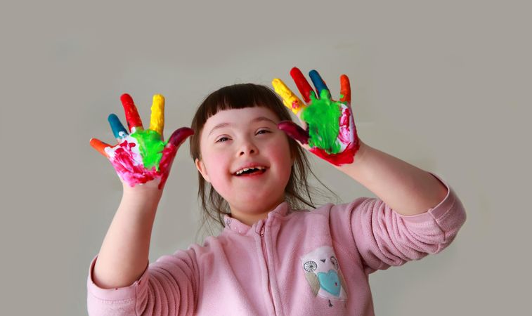 Happy little girl finger painting her hands