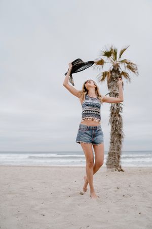 Young female relaxing on beach with hat