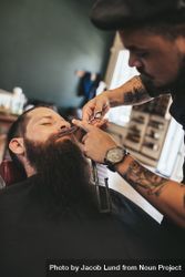 Barber trimming mustache of customer in his salon 5r36d4