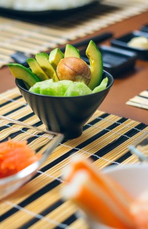 Detail of bowl of avocado cut along with other ingredients ready to prepare sushi, vertical