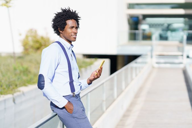 Man looking in the distance with his phone on a sunny day