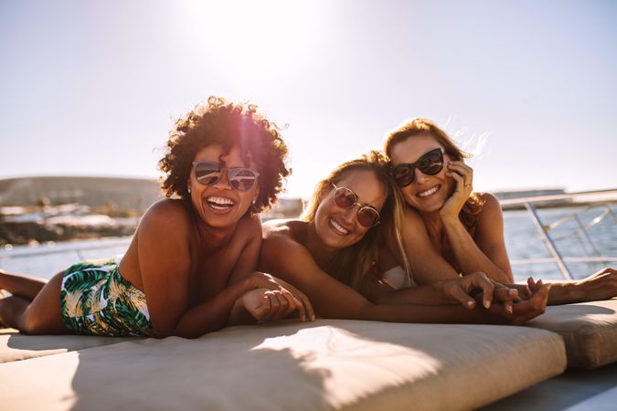 Beautiful women wearing swimsuits and sunglasses while sunbathing