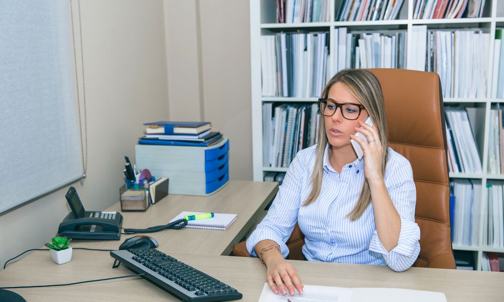 Blonde businesswoman talking with phone in the office