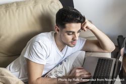 Young man relaxing on couch while using laptop 41lJJO