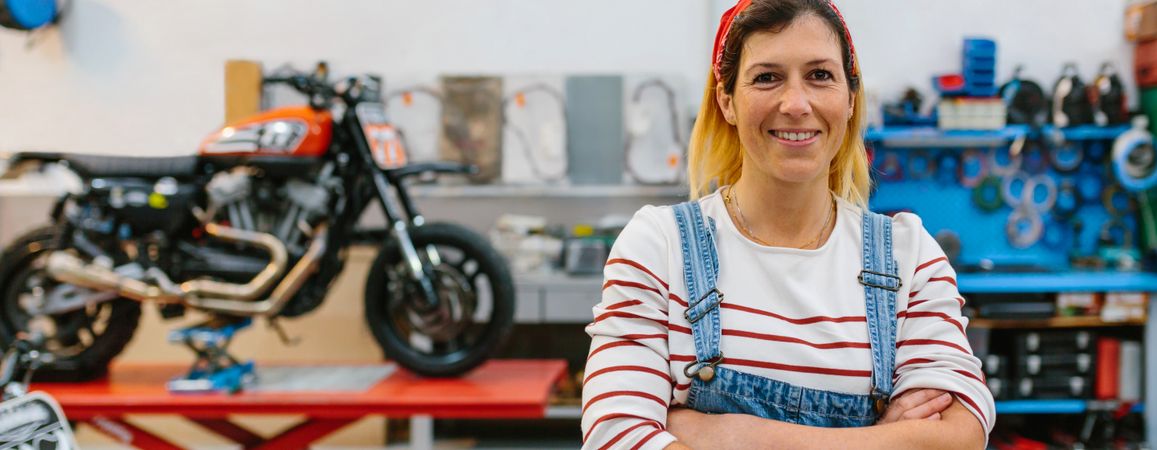 Portrait of mechanic woman standing on motorcycle factory