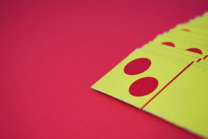 Red and yellow domino playing cards on red table with copy space