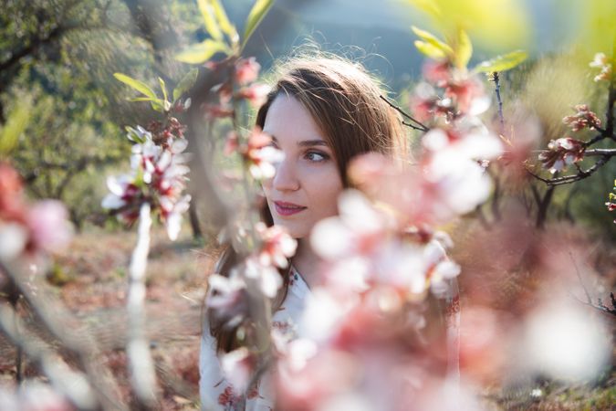 Young happy woman between trees in garden