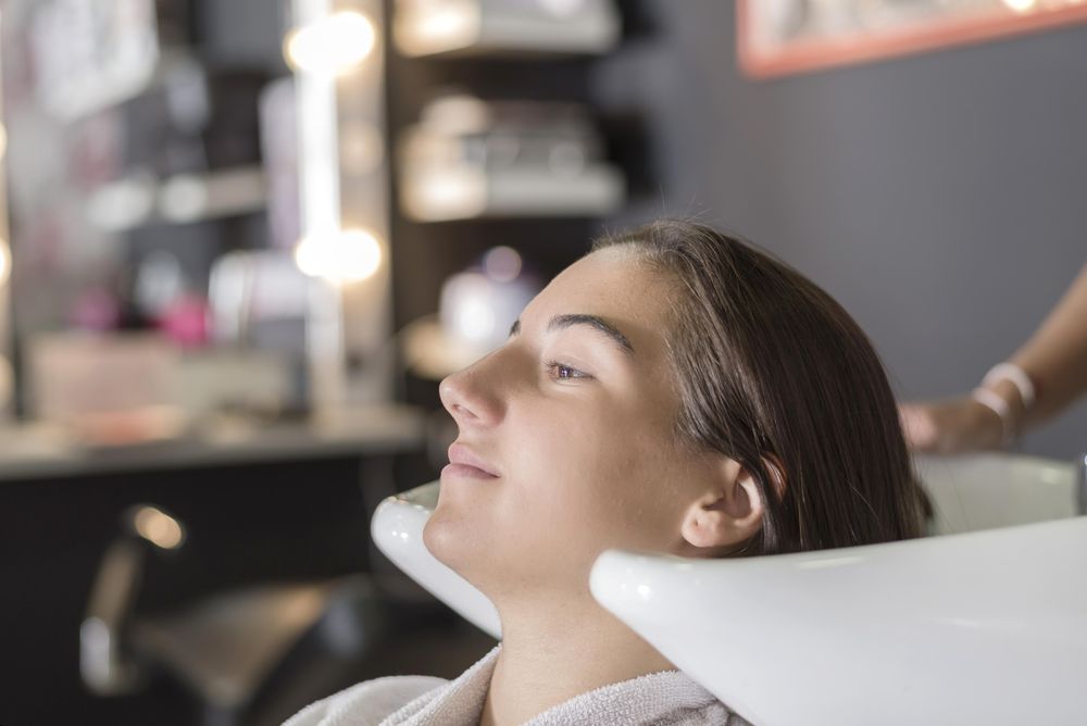 Female sitting with head back in sink at hairdressers awaiting a shampoo