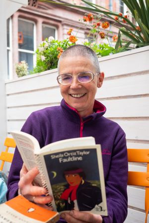 Older woman with short hair  smiling while reading Miss Hargreaves