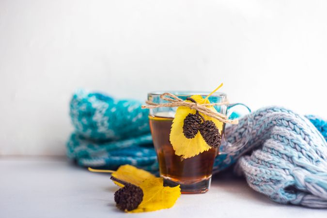Side view of autumnal tea with pine cones wrapped in blue scarf