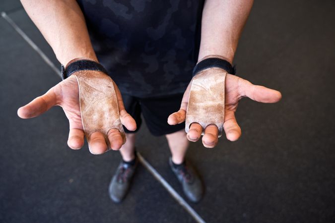 Crop man in gymnastic pads showing hands