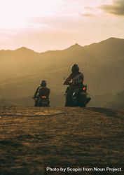 Two people riding mountain motorcycle on brown field at sunset 0KZ7Yb