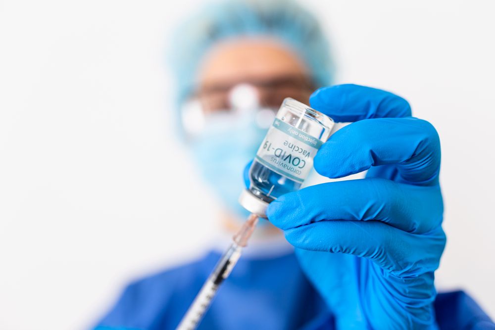 Doctor extracting coronavirus vaccine using syringe
