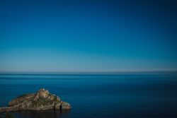 Lonely island amid sea tranquility under perfect blue sky