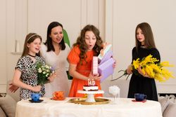 Young girl expressing surprise at birthday gift with family