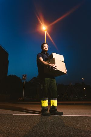 Courier delivering cardboard boxes in evening