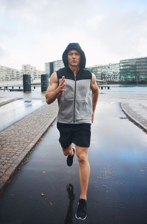 Muscular man running outside on overcast cast, vertical