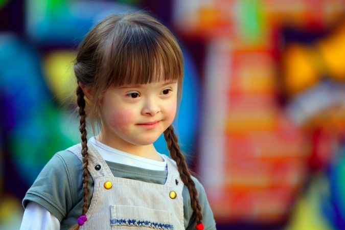 Girl with Down syndrome and braided hair against a colorful background