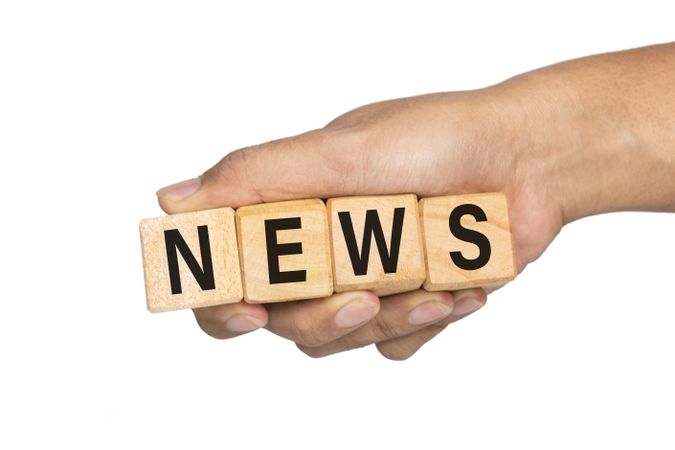 male hand holding wooden cubes with news word