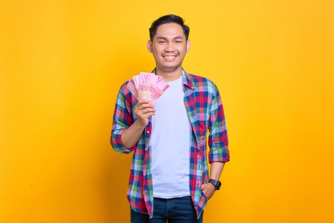 Asian man with cash in one hand in studio shoot
