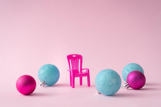Pink outdoor chair on pink background with Christmas bauble decorations