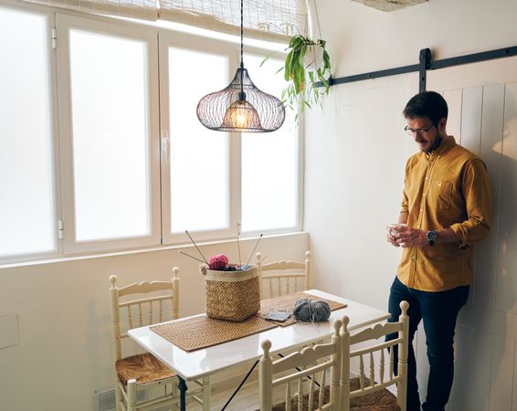 Man drinking hot tea during knitting