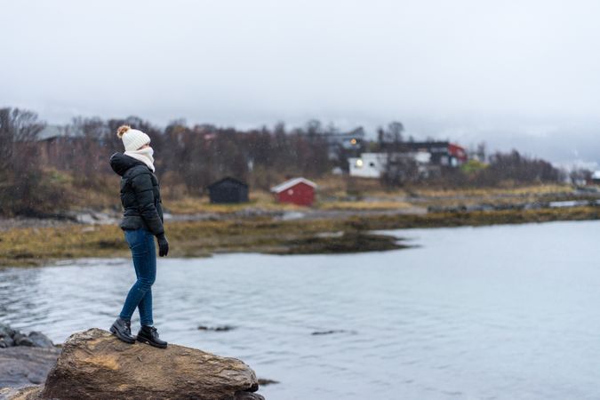 Female standing on stone cliff off coast