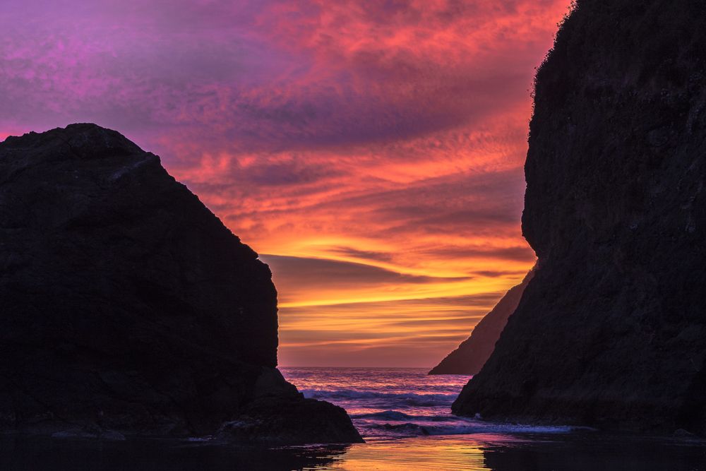 Pink and bright yellow sunset between coastal rocks