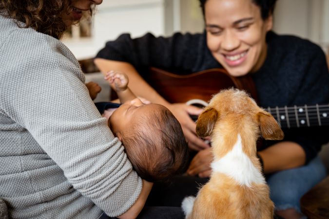 Woman playing acoustic guitar for baby, partner and pets
