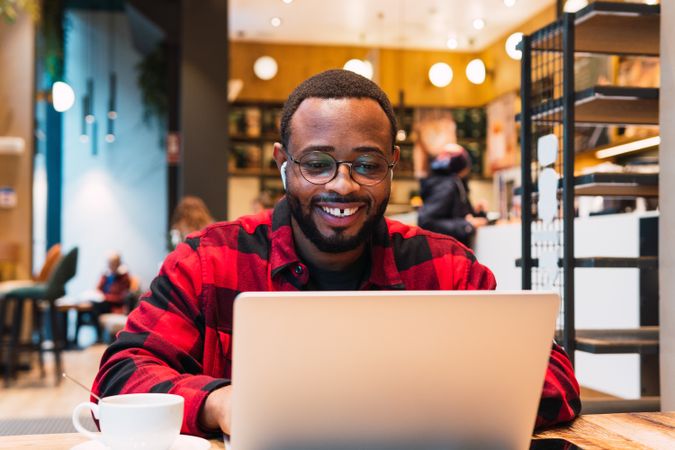 Smiling Black man working on laptop in cafe