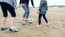 Three female generations playing soccer on the beach